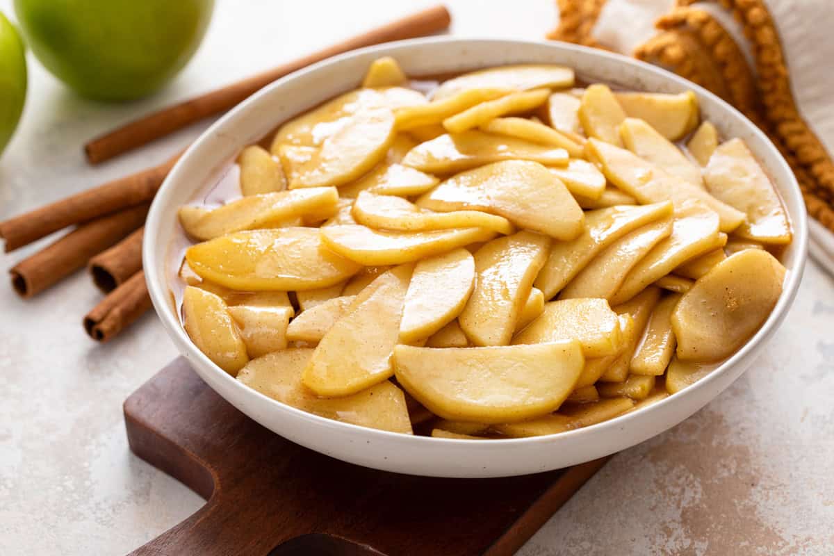 White bowl filled with sauteed cinnamon apples.