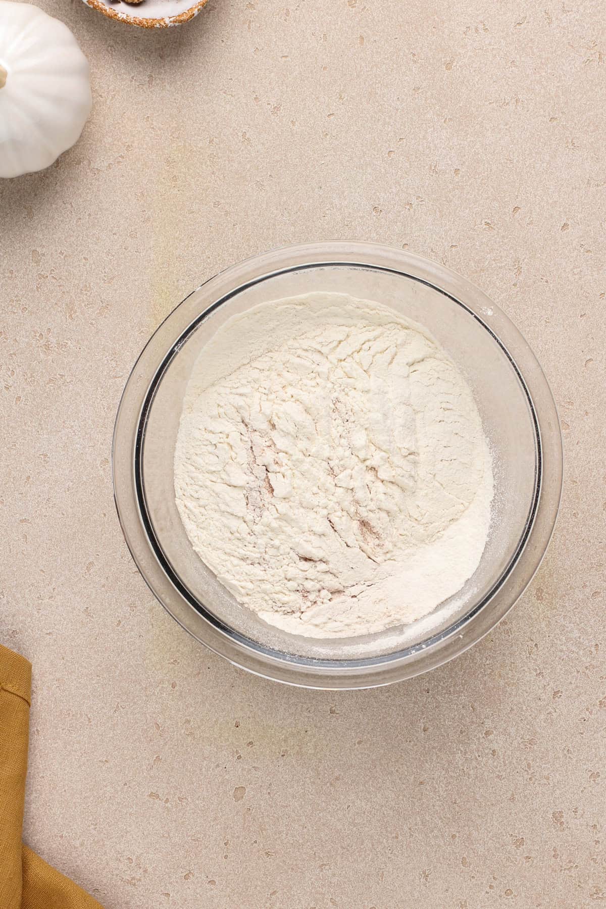 Dry ingredients for pumpkin bars combined in a glass bowl.