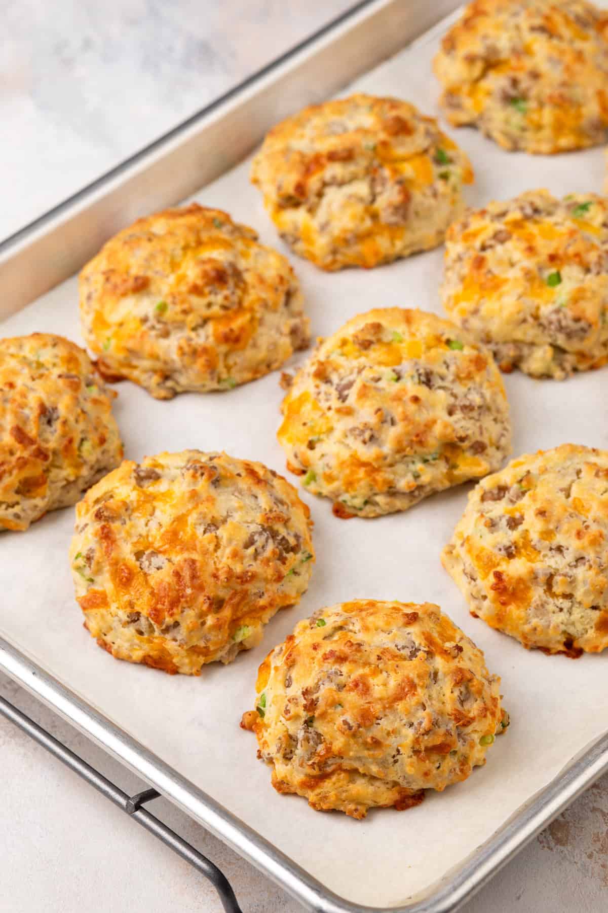 Baked sausage biscuits on a parchment-lined sheet pan.