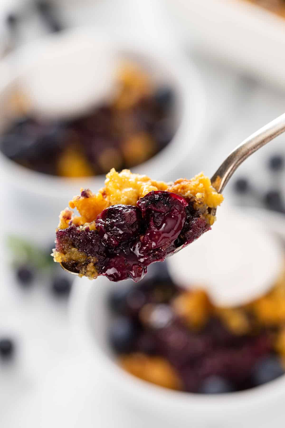 Spoon holding up a bite of blueberry dump cake.