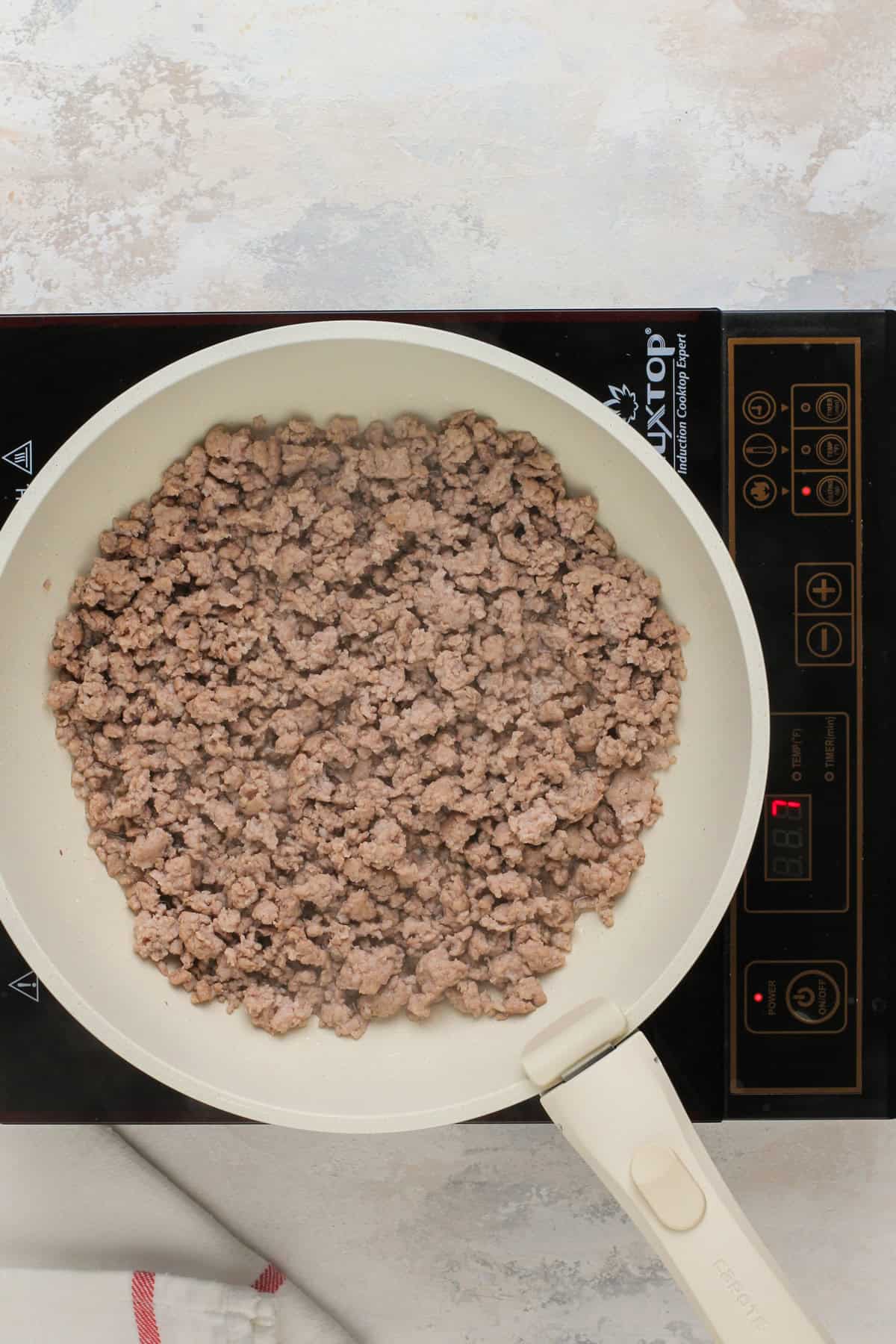 Cooked and crumbled breakfast sausage in a skillet.