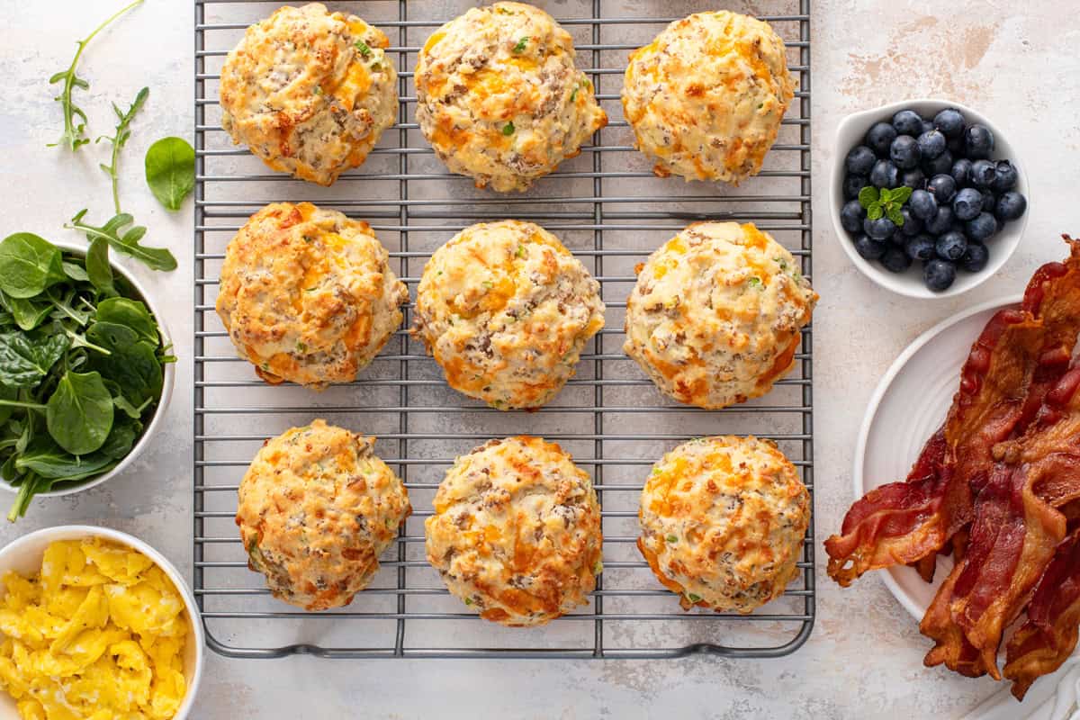 Cheesy sausage biscuits lined up on a wire cooling rack.