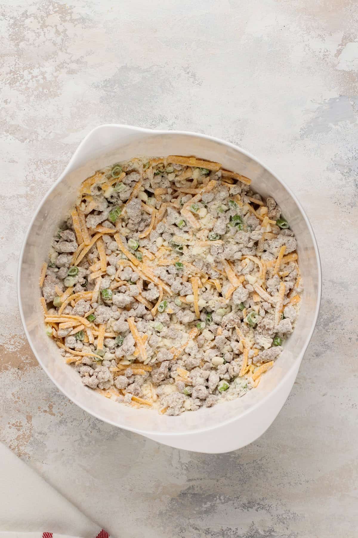 Cooked sausage, shredded cheese, and green onions stirred into dry ingredients for cheesy sausage biscuits.