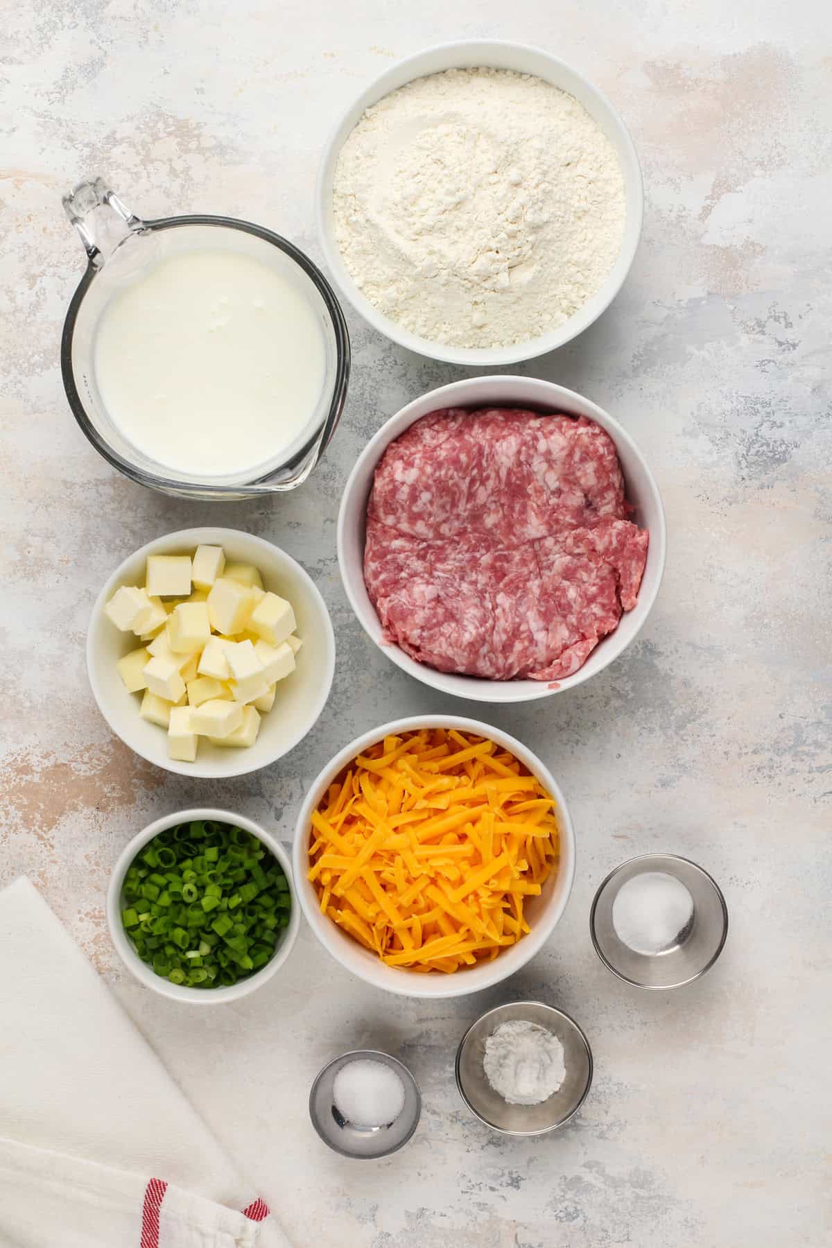 Ingredients for cheesy sausage biscuits arranged on a countertop.