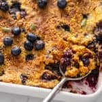Serving spoon in a pan of blueberry dump cake.