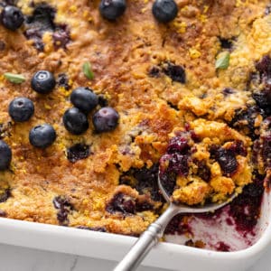 Serving spoon in a pan of blueberry dump cake.