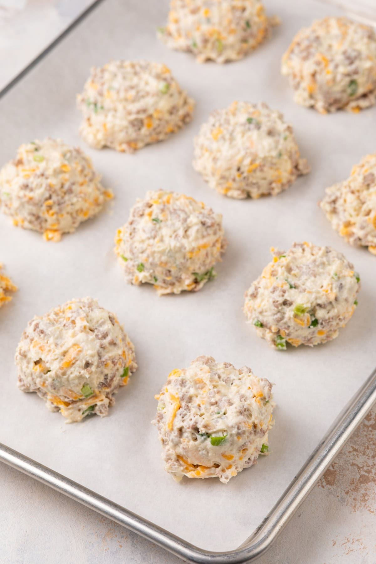 Unbaked sausage biscuits on a sheet pan, ready to go in the oven.
