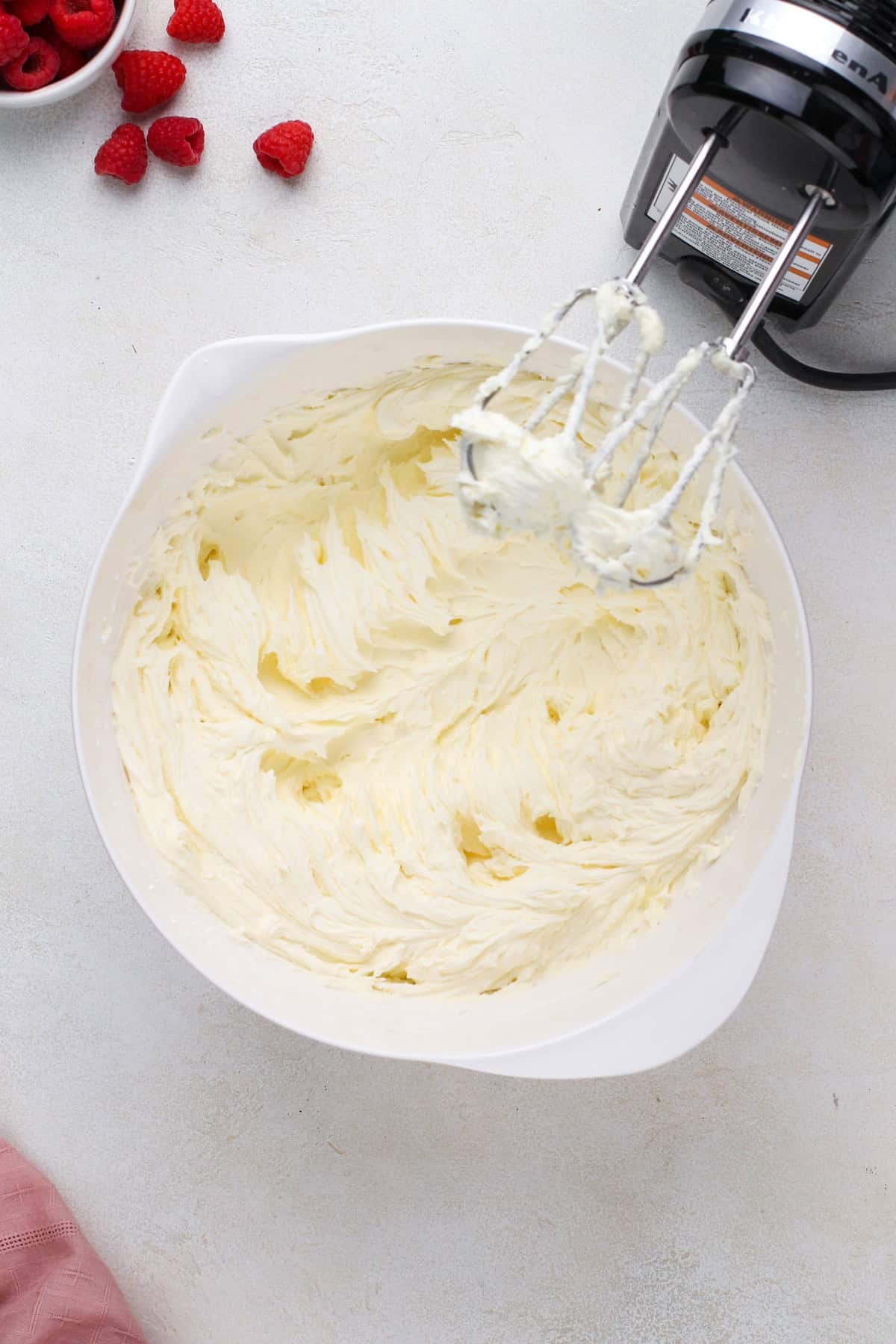 Powdered sugar mixed into beaten butter in a white bowl.