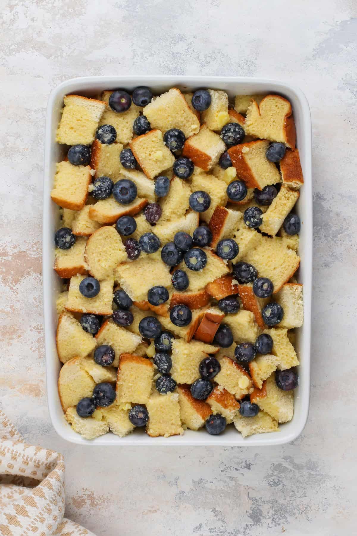 Assembled blueberry french toast casserole in a white baking dish, ready to go in the oven.