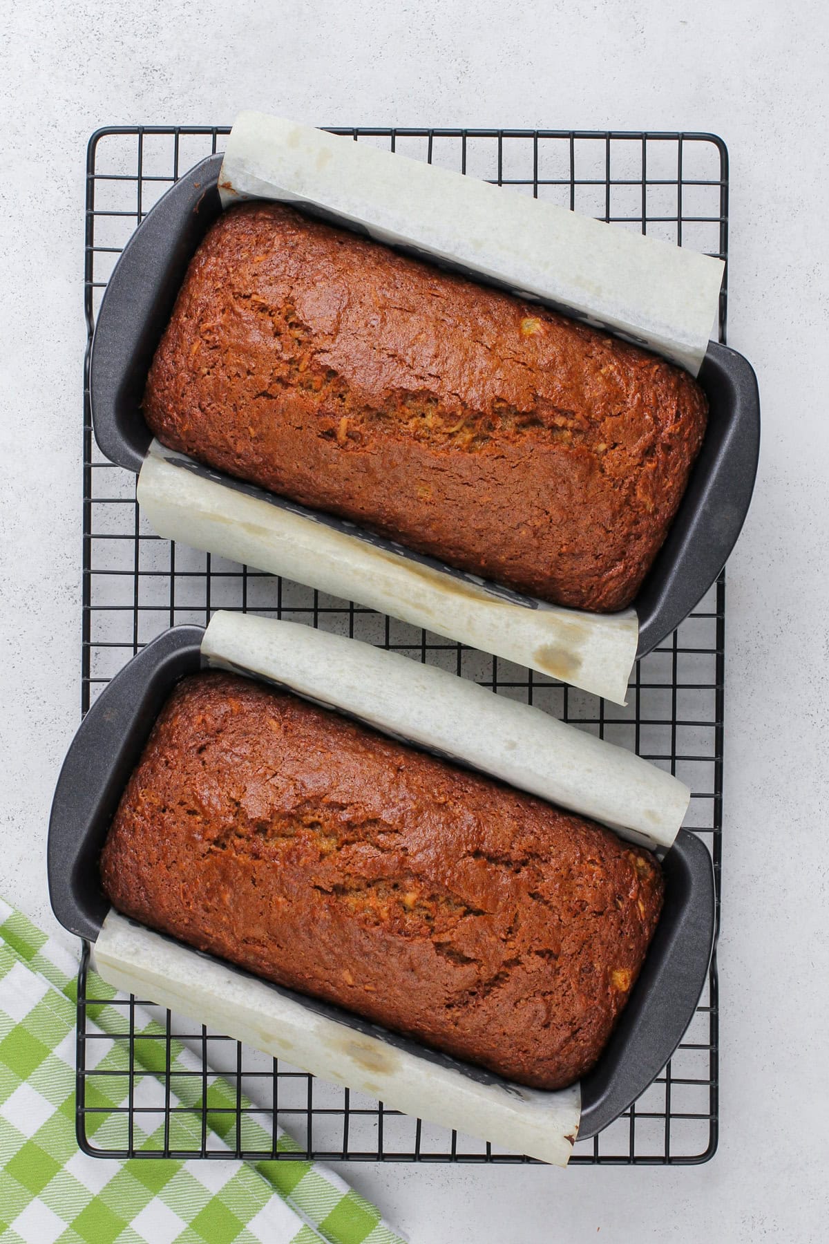 Two loaves of carrot cake bread cooling on a wire rack.