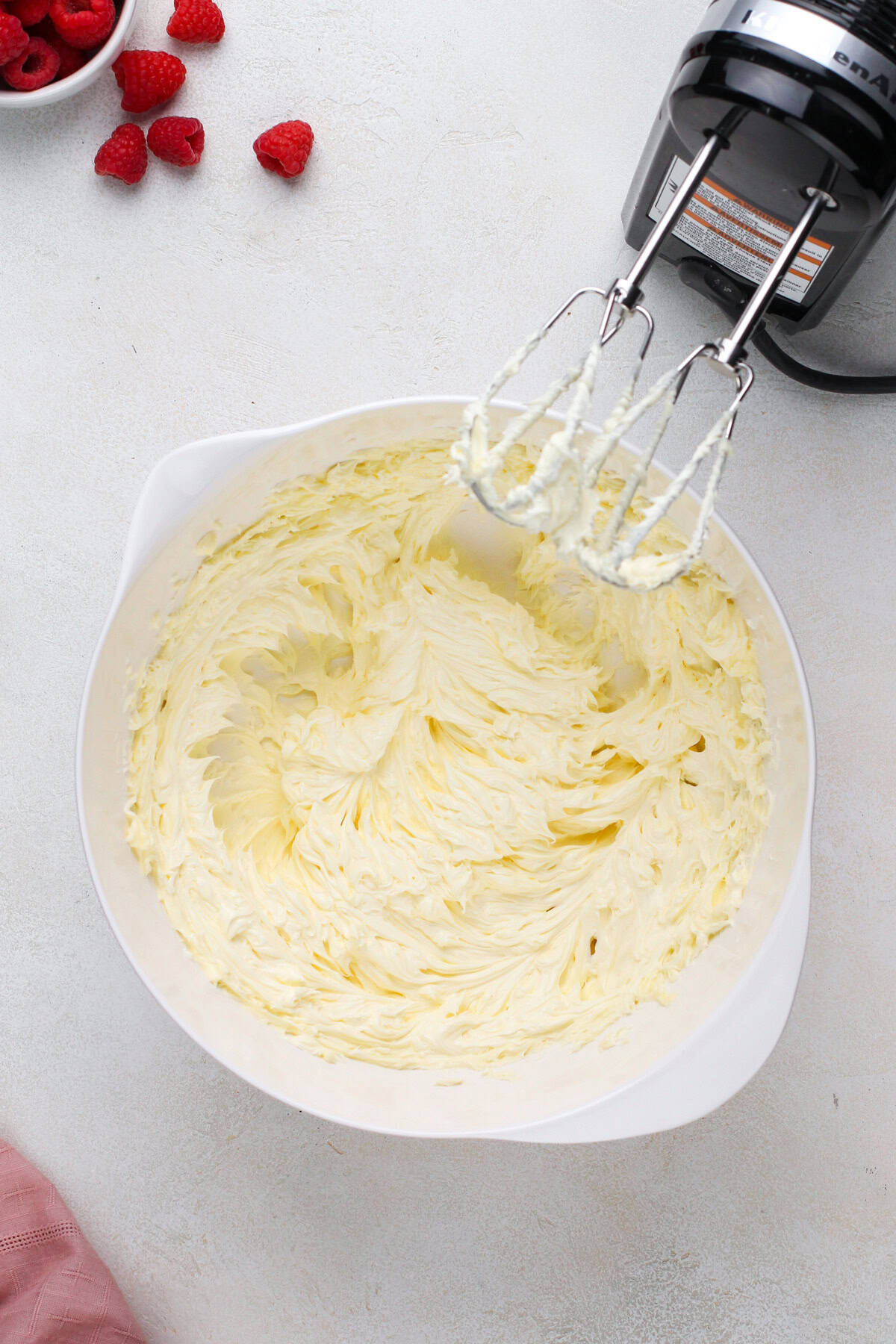 Butter beaten with a mixer in a white bowl.
