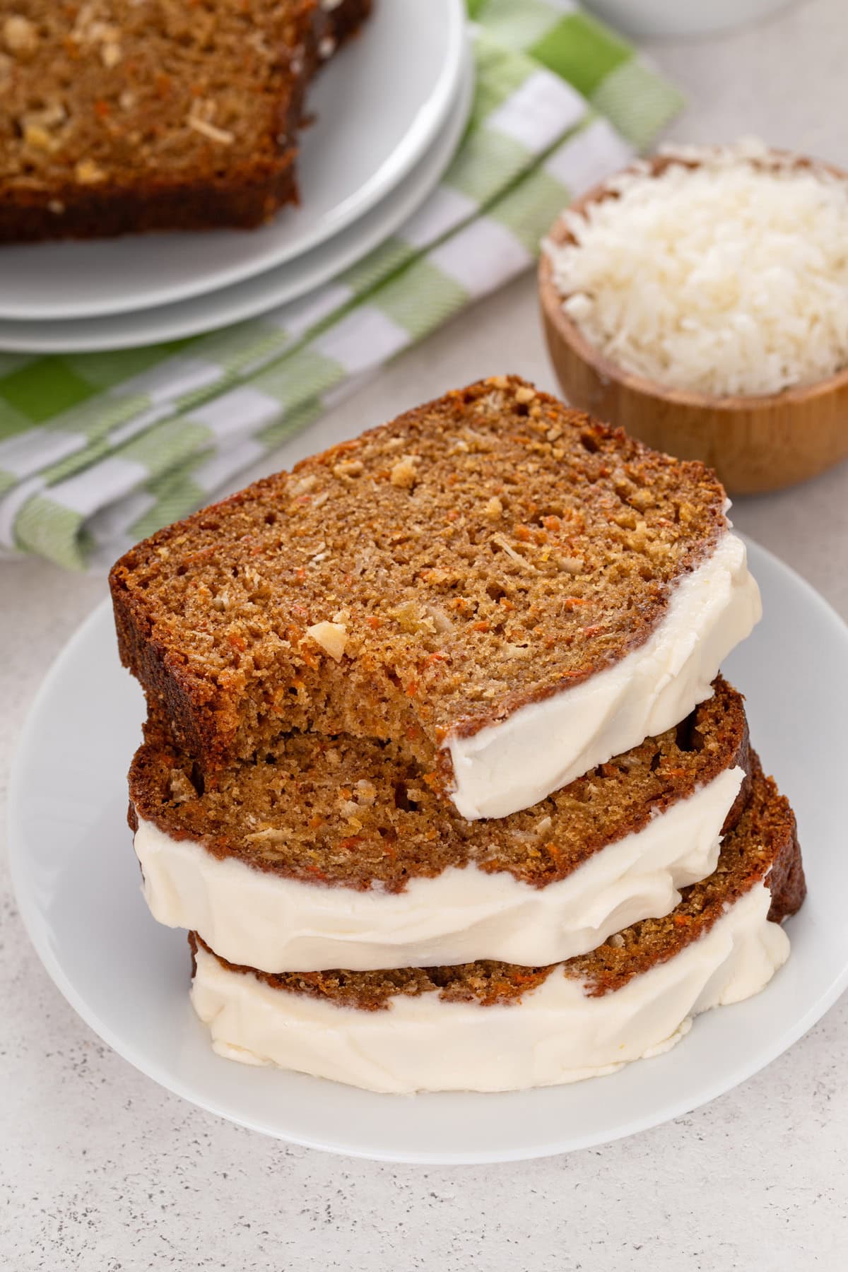 Three stacked slices of carrot cake bread, with a bite taken from the top slice.