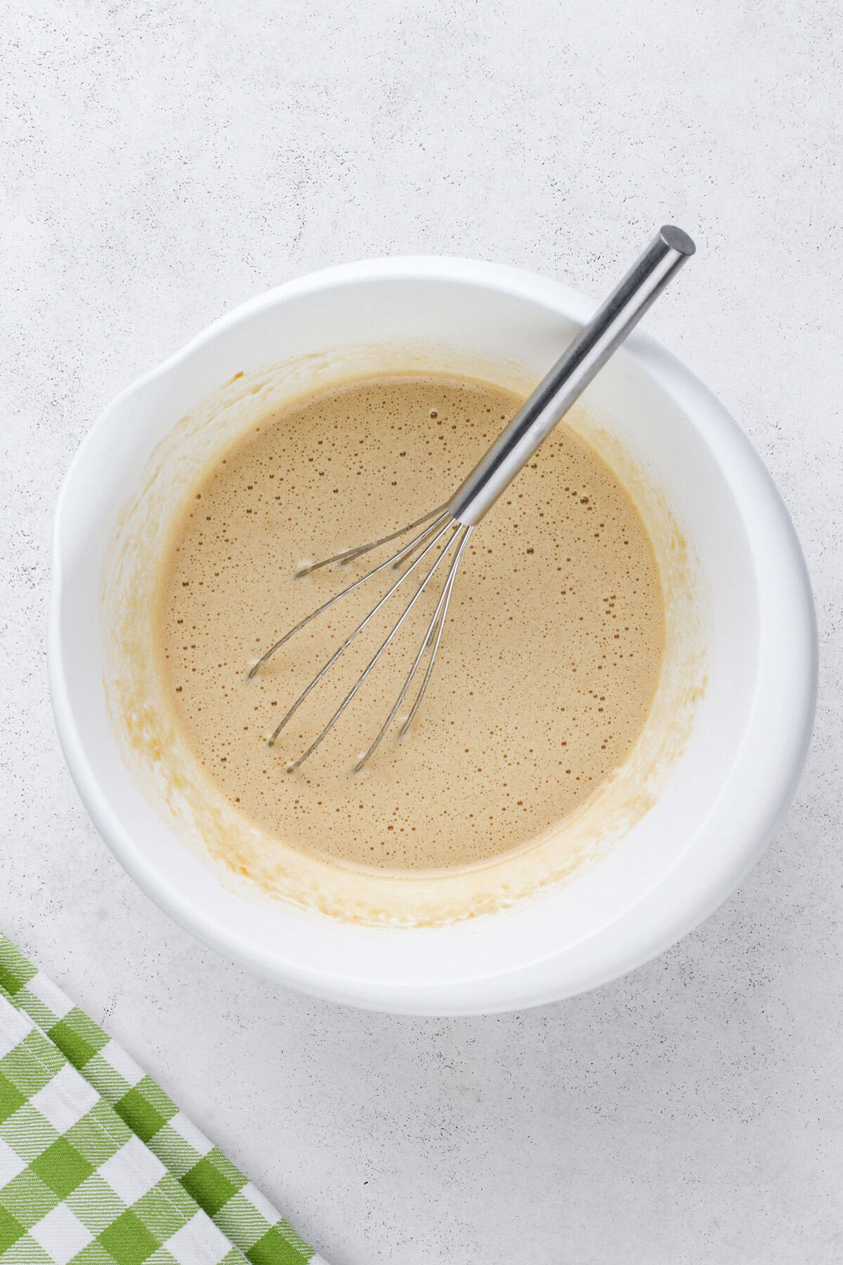 Wet ingredients for carrot cake bread whisked in a white bowl.