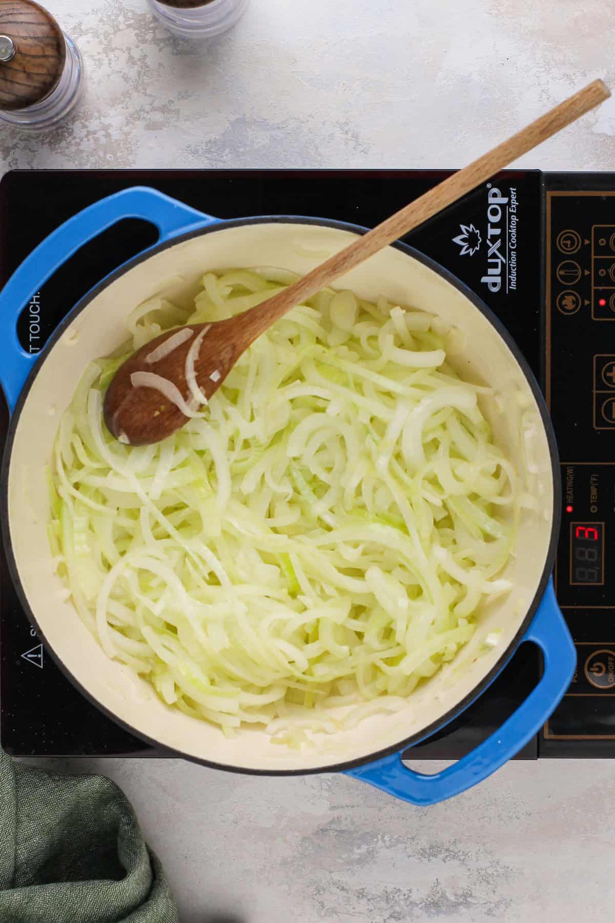 Sliced onions added to a dutch oven for caramelizing.