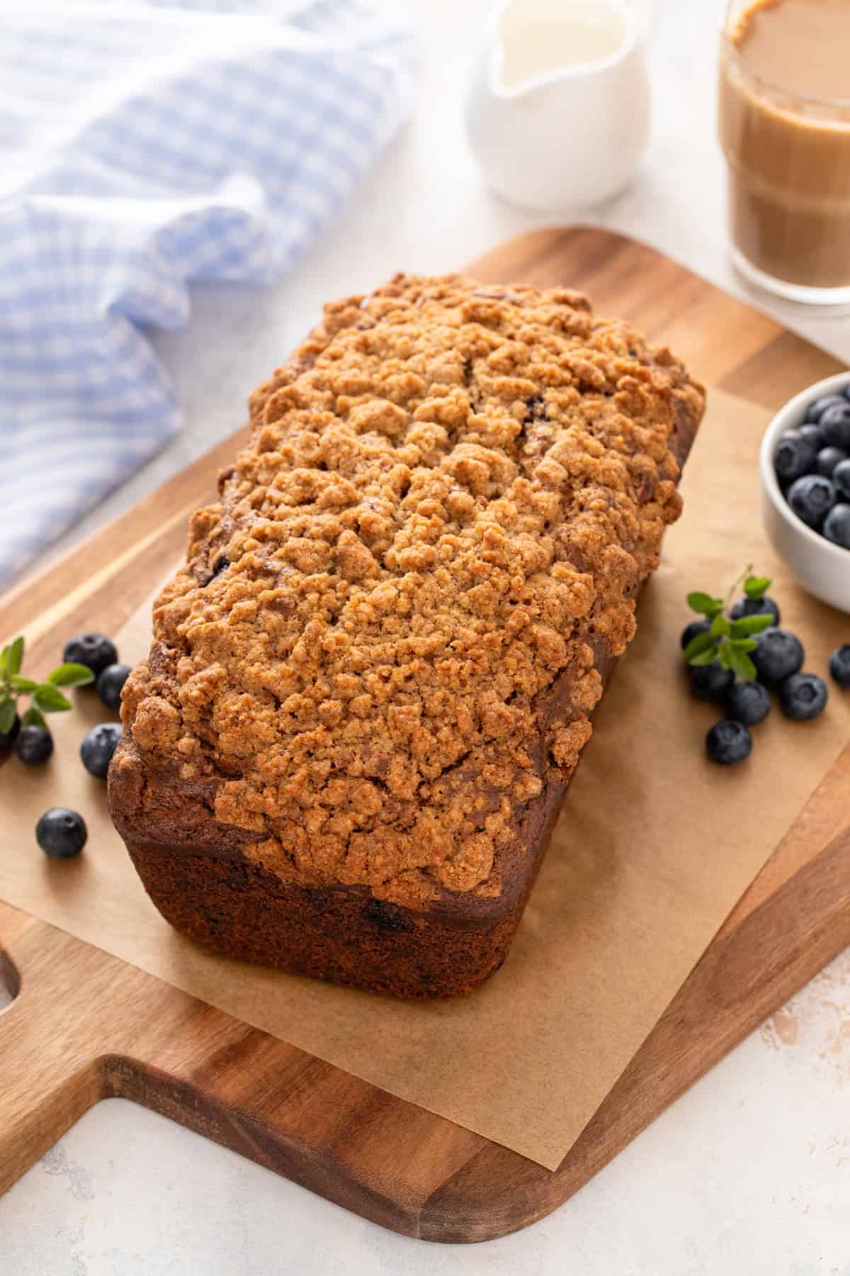 Cooling loaf of blueberry banana bread on a wooden board.