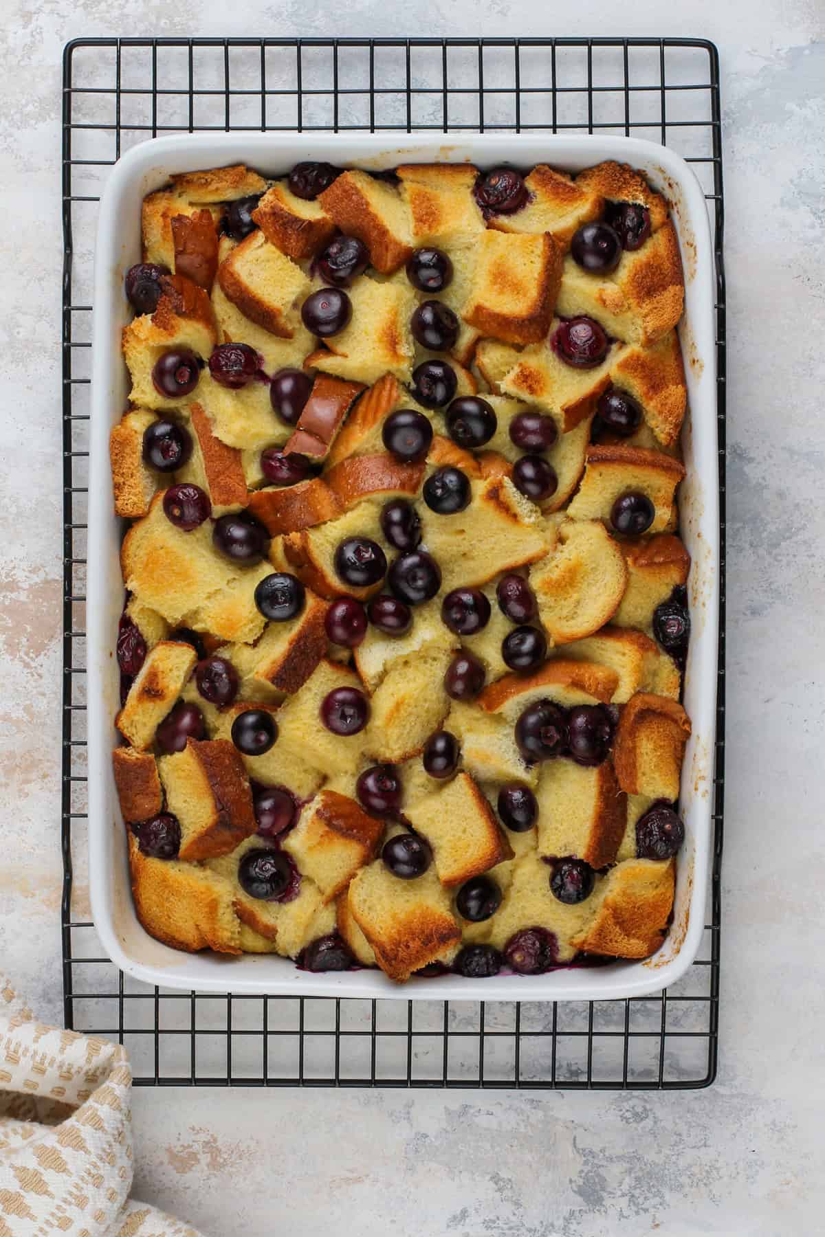 Baked blueberry french toast casserole resting on a wire cooling rack.