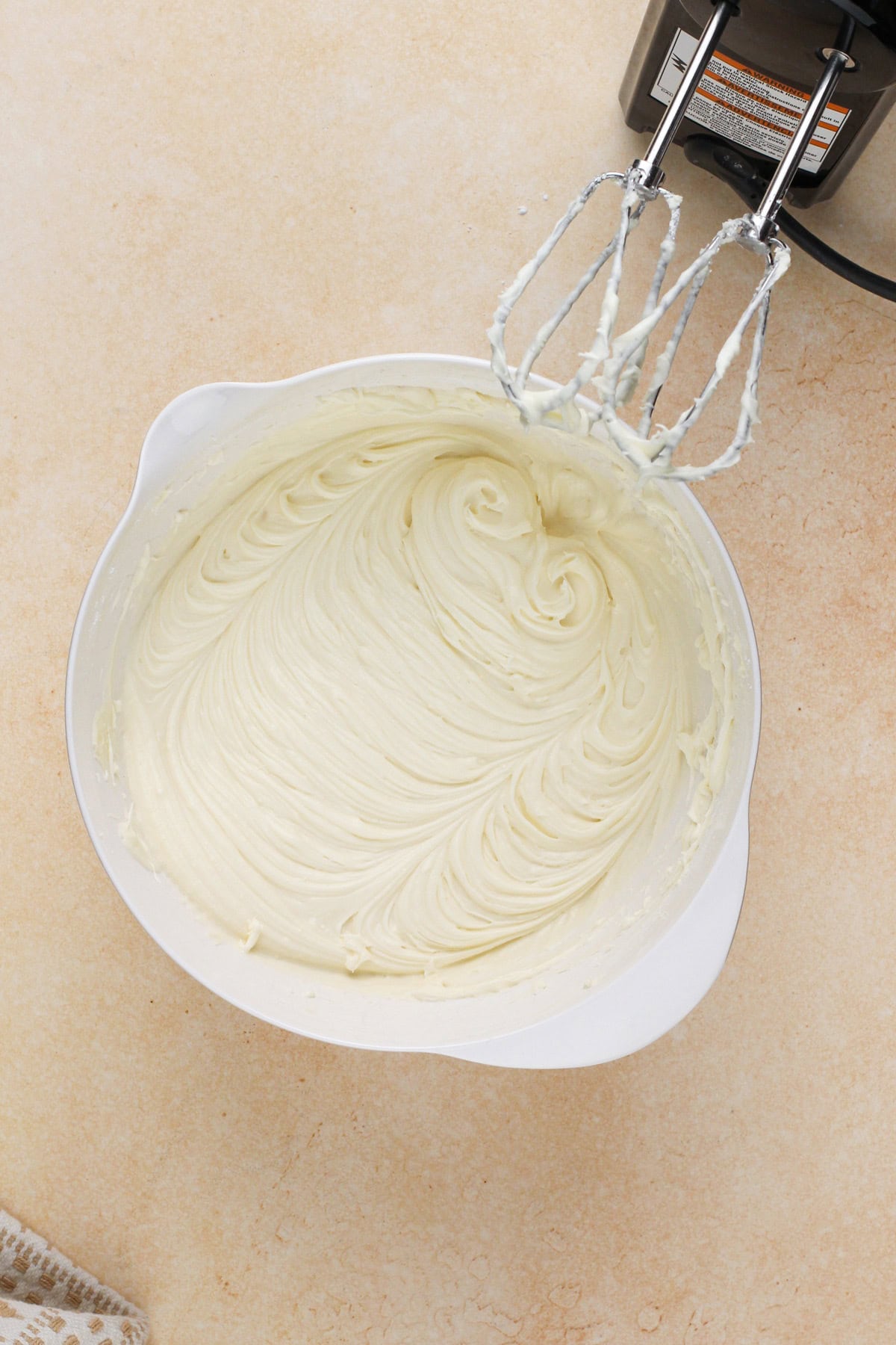 Cream cheese frosting for carrot cake bars mixed in a white bowl.