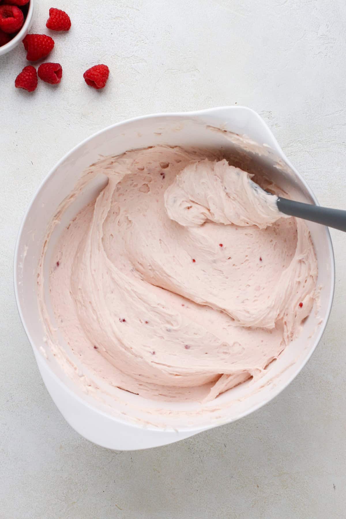 Finished raspberry buttercream frosting in a white mixing bowl.