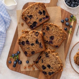 Four slices of blueberry banana bread on a wooden board.