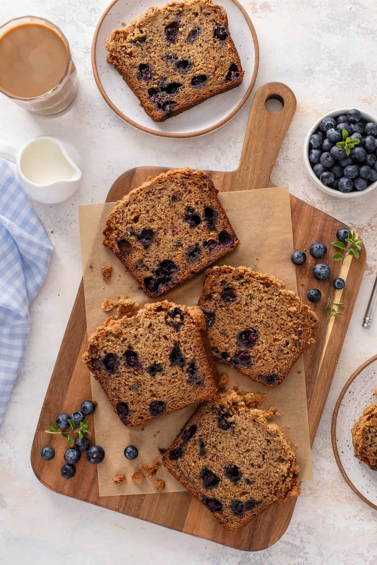 Overhead view of four slices of blueberry banana bread on a wooden board.