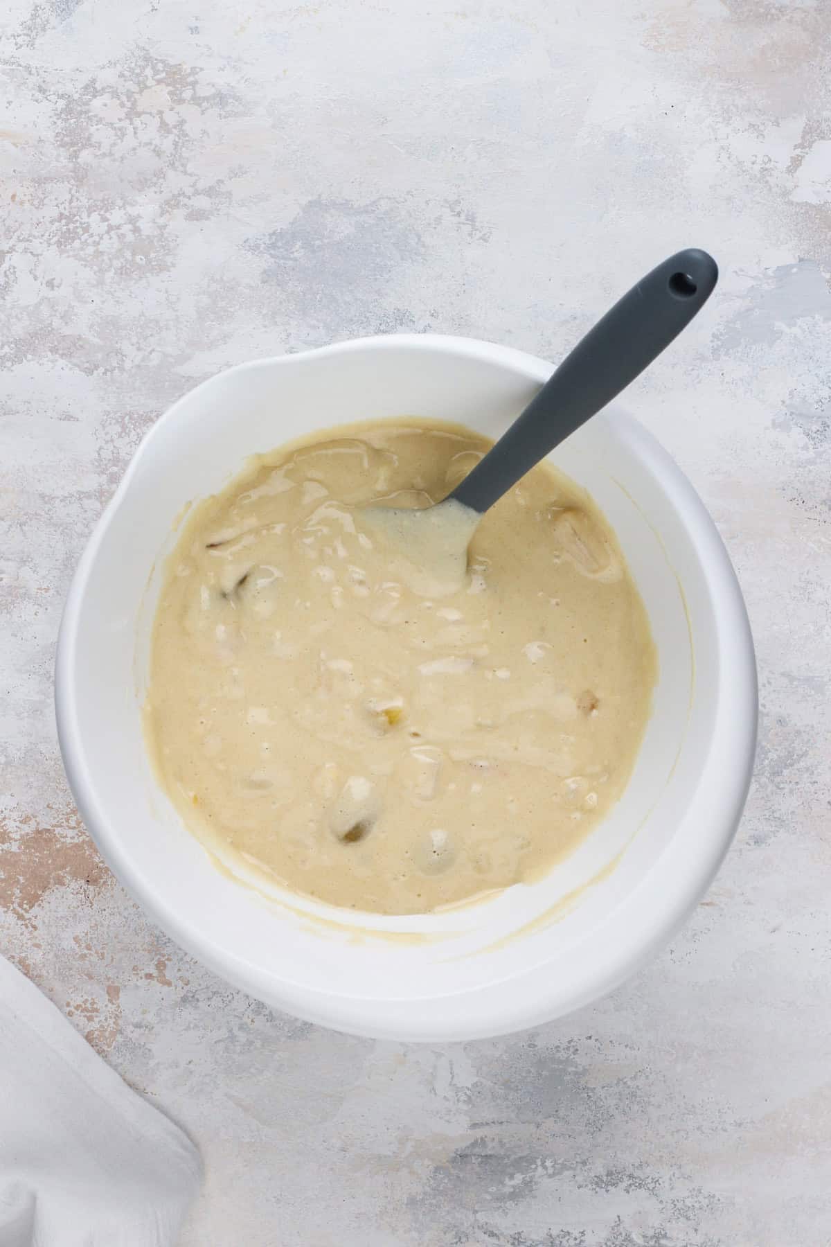 Batter for fruit cocktail cake mixed in a white bowl.
