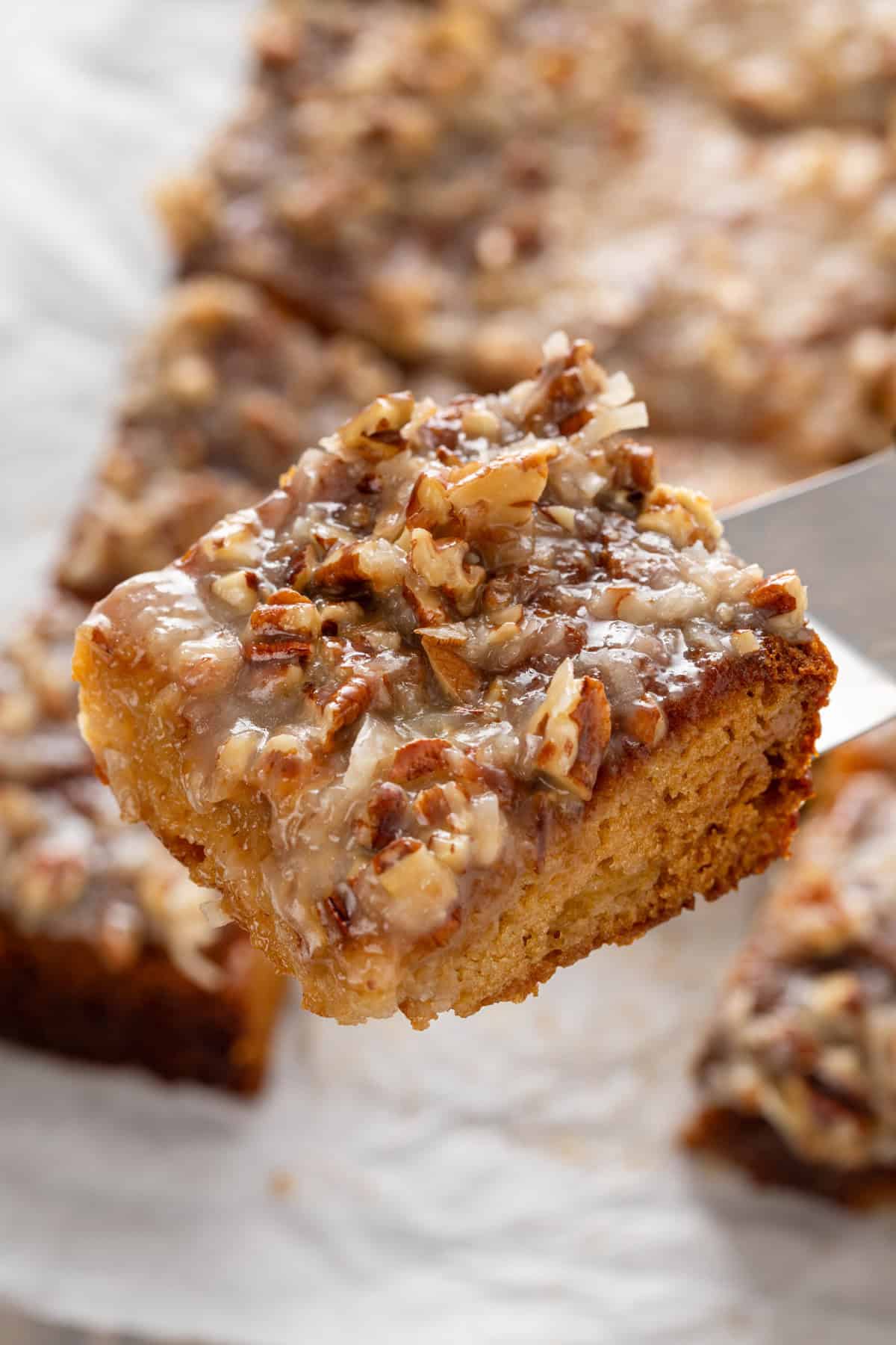 Cake server holding up a slice of fruit cocktail cake.