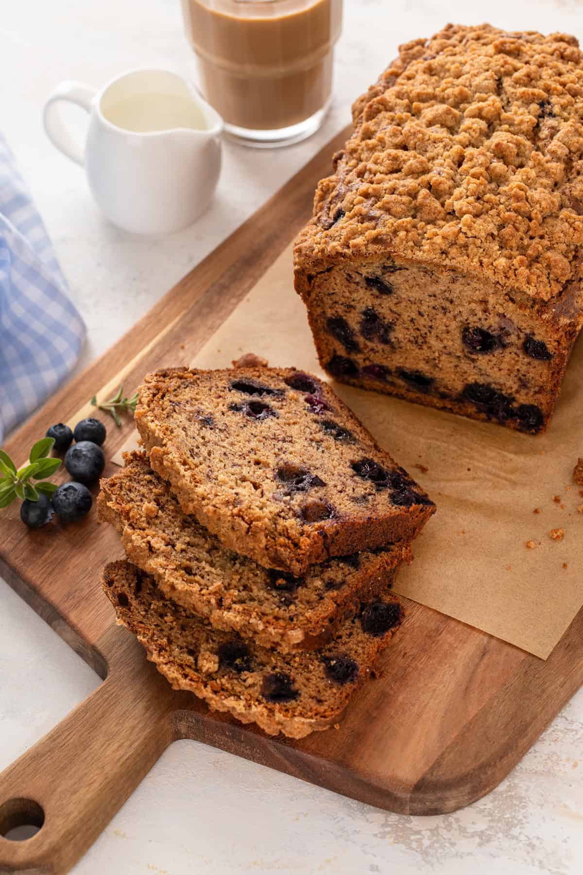 Sliced loaf of blueberry banana bread on a wooden board.