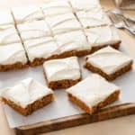 Slices of carrot cake bars on a wooden board.
