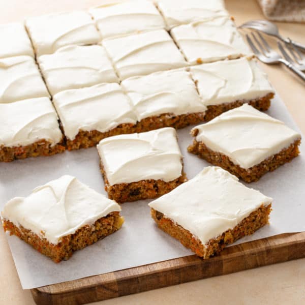 Slices of carrot cake bars on a wooden board.