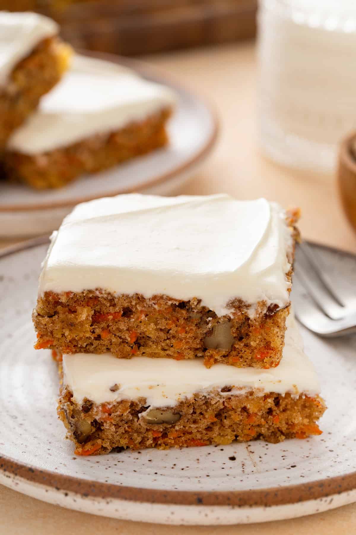 Two carrot cake bars stacked on a plate.