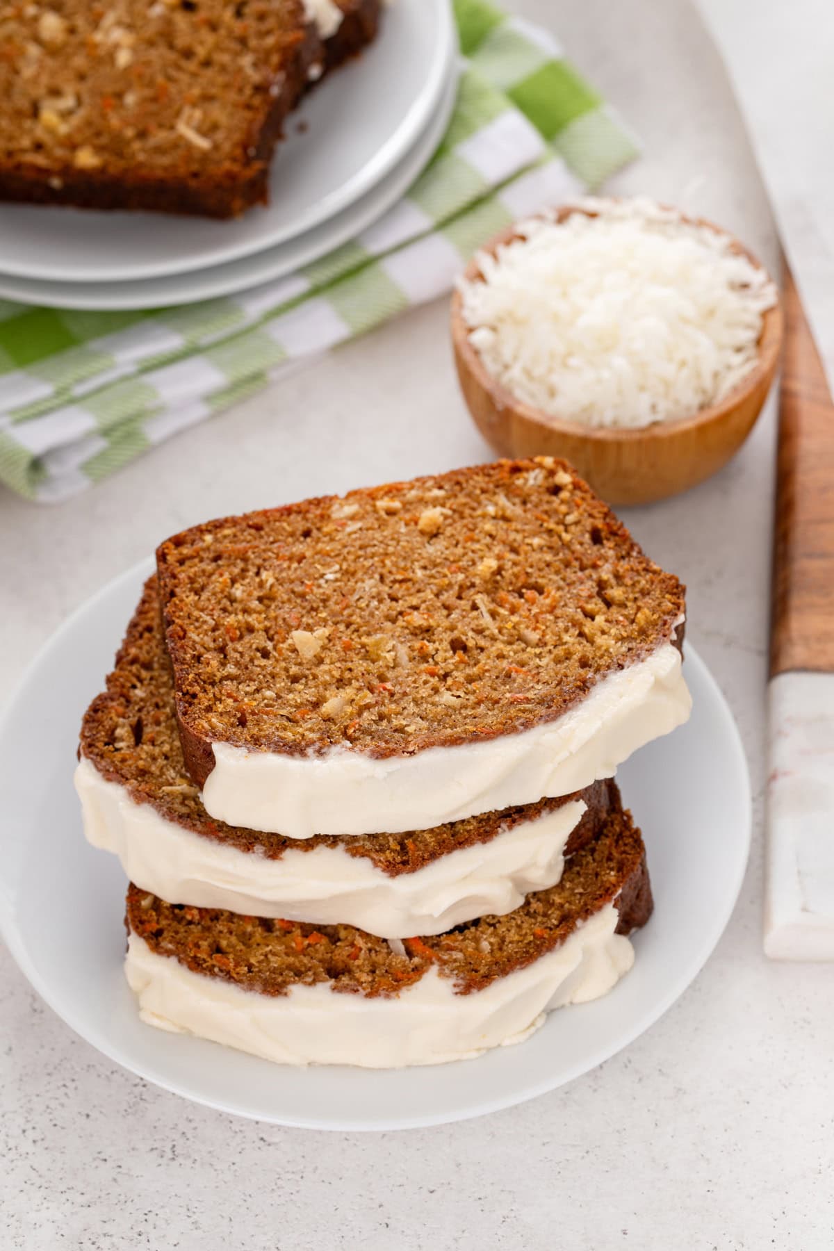 Three slices of carrot cake bread stacked on a white plate.