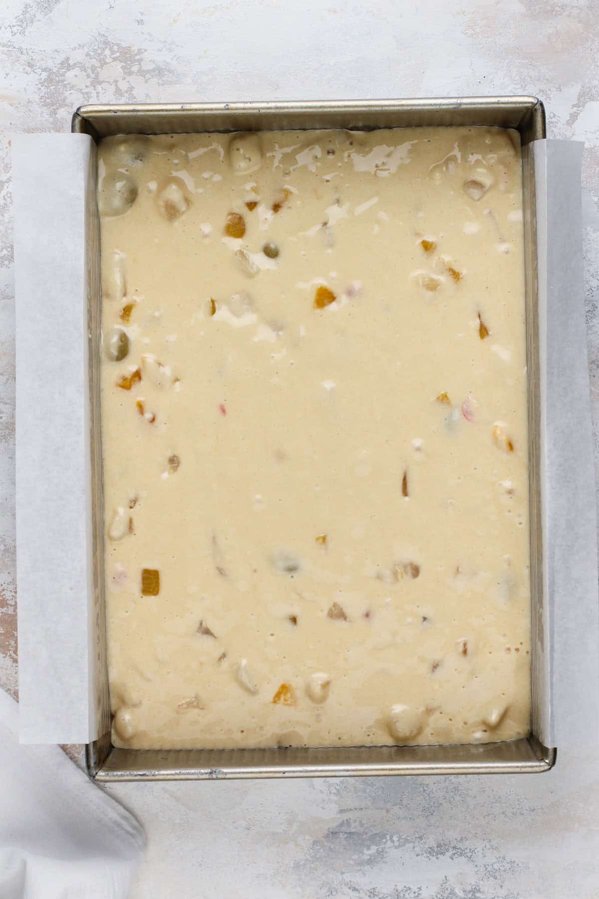 Batter for fruit cocktail cake spread into a cake pan.