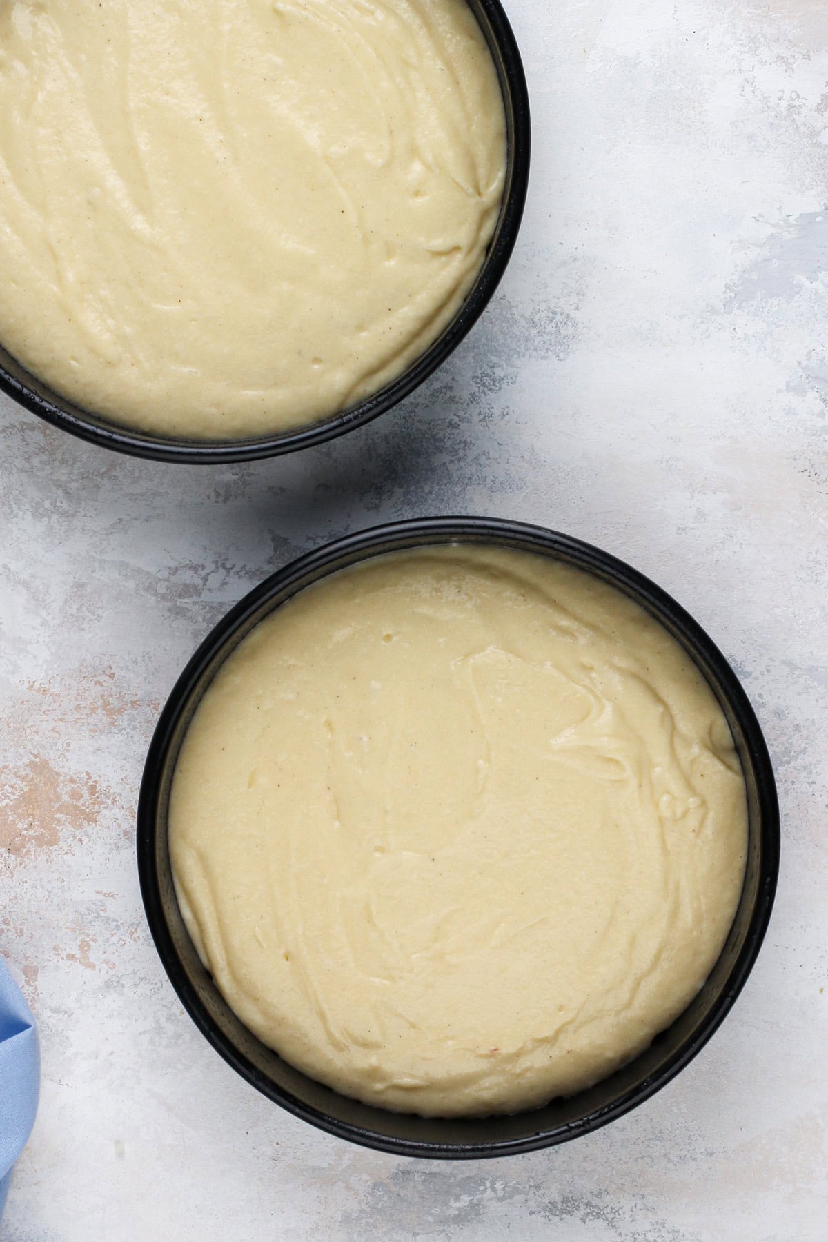 Vanilla cake batter in two cake pans, ready to go in the oven.