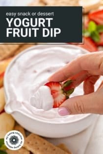 Hand holding up a halved fresh strawberry that's been dipped in yogurt fruit dip. Text overlay includes recipe name.