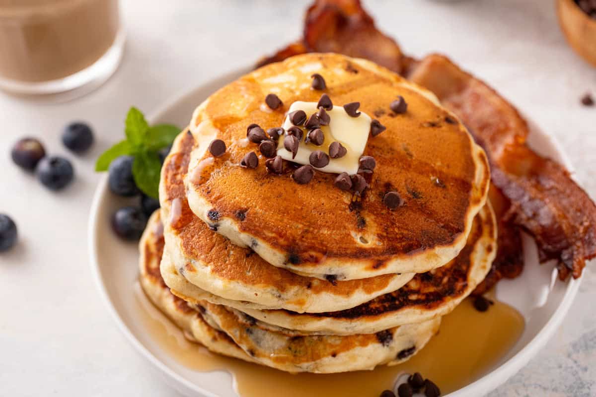 Plated stack of chocolate chip pancakes topped with butter and syrup.