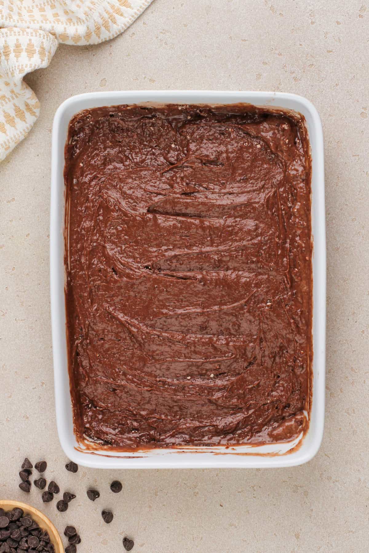 Batter for chocolate dump cake spread into a white baking dish.