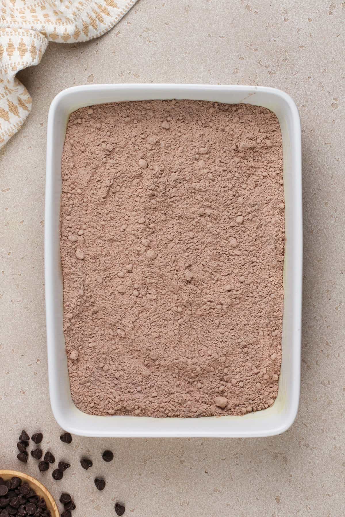 Chocolate dump cake dry ingredients in a white baking dish.
