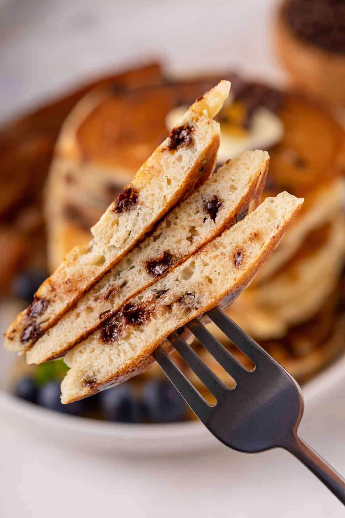 Fork holding up a bite of chocolate chip pancakes.