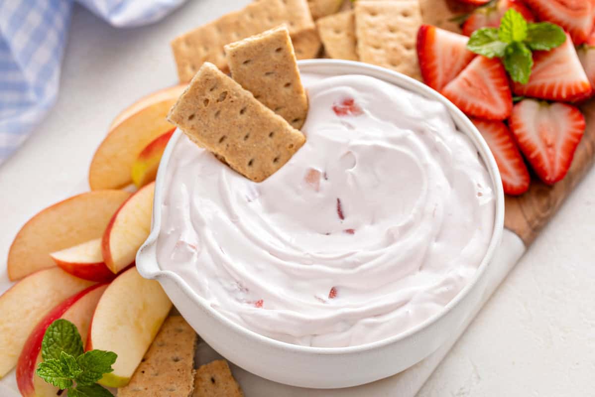 White bowl filled with yogurt fruit dip with two graham crackers arranged at the edge of the bowl.