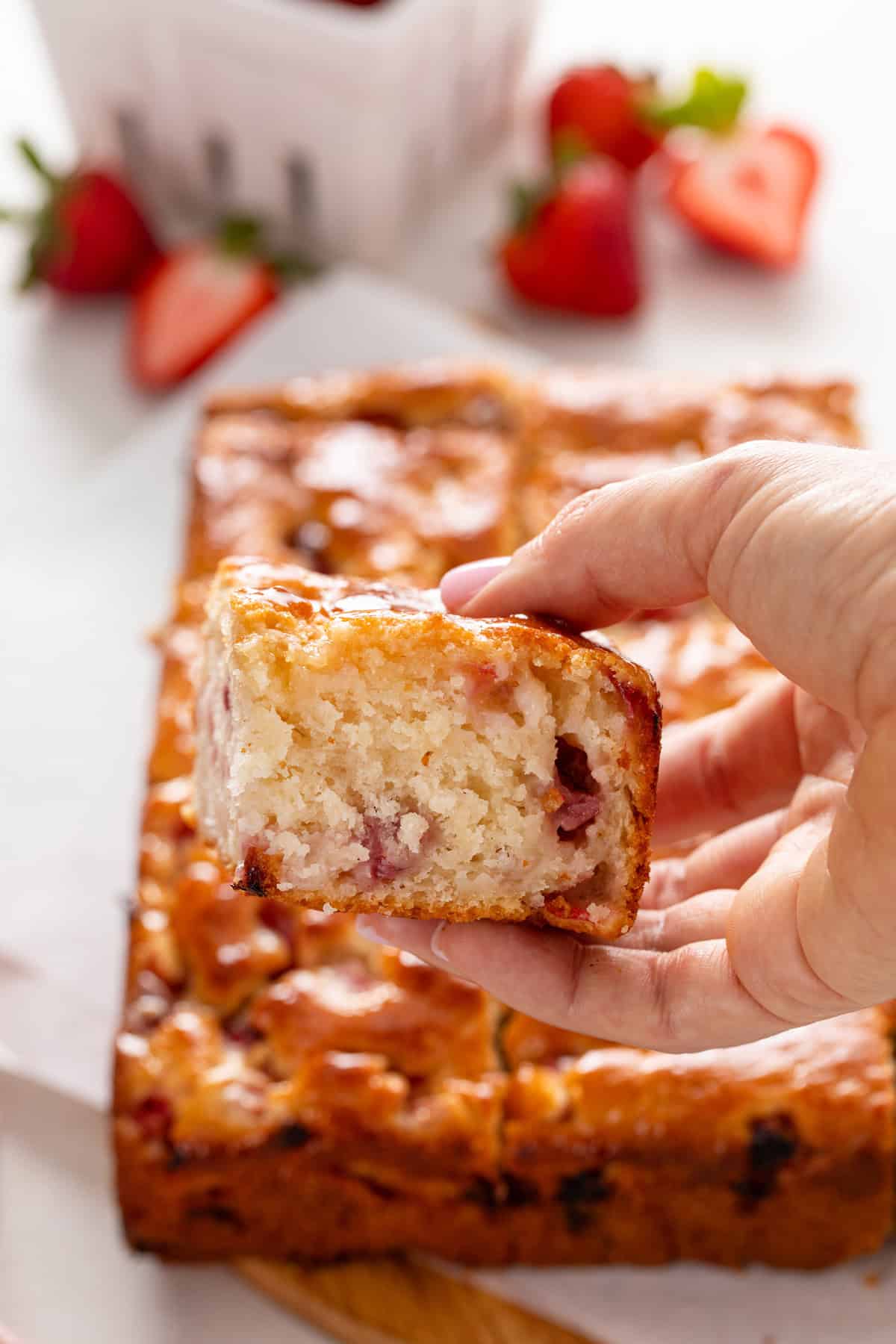 Hand holding up a strawberry biscuit to the camera.