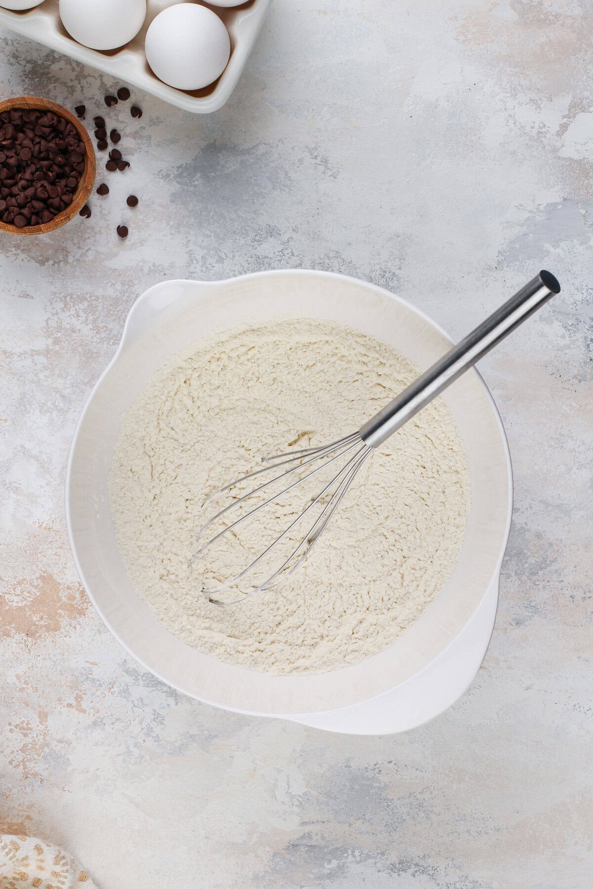 Dry ingredients for chocolate chip pancakes whisked in a white bowl.