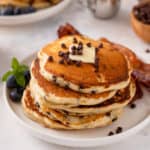 Stack of chocolate chip pancakes on a white plate.