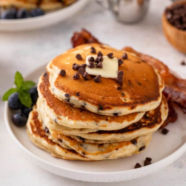 Stack of chocolate chip pancakes on a white plate.