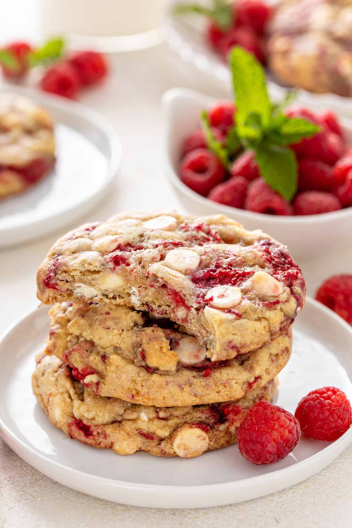 Stack of 4 white chocolate raspberry cookies with a bite taken from the top cookie.