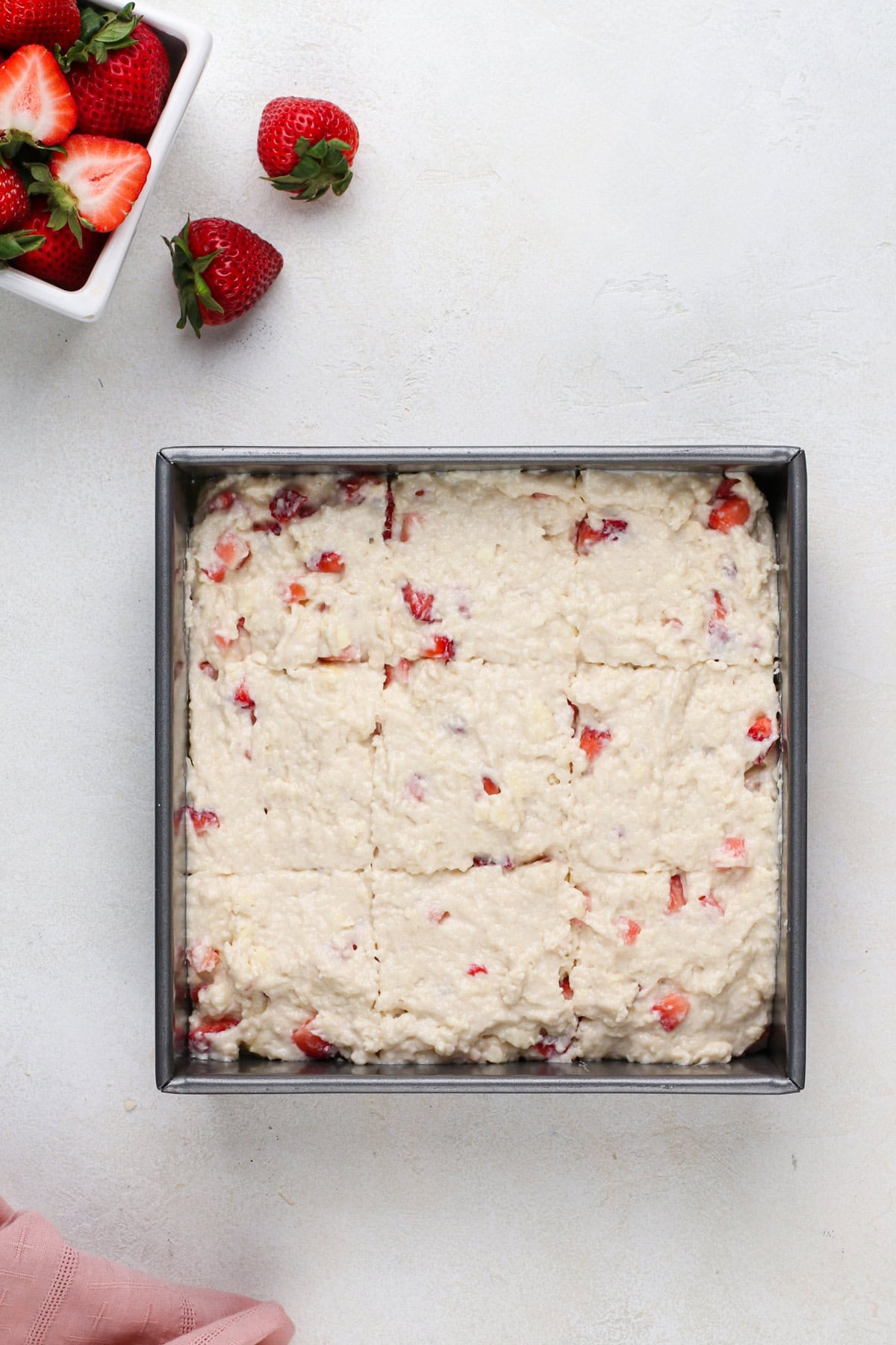 Strawberry biscuit dough spread into a baking pan.