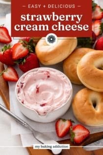 Wooden board filled with bagels, fresh strawberries, and a bowl of strawberry cream cheese. Text overlay includes recipe name.