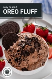 Small white bowl filled with oreo fluff set on a white plate with oreo cookies and fresh strawberries. Text overlay includes recipe name.