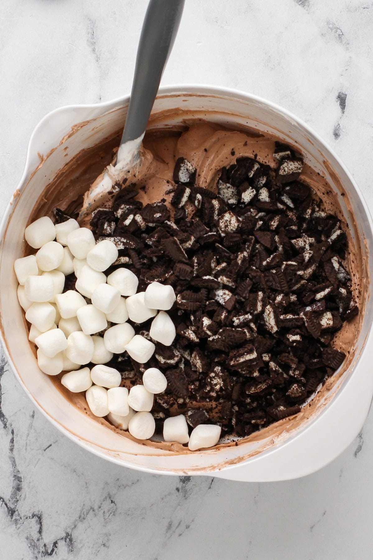 Crushed oreos and mini marshmallows being added to a bowl for oreo fluff.