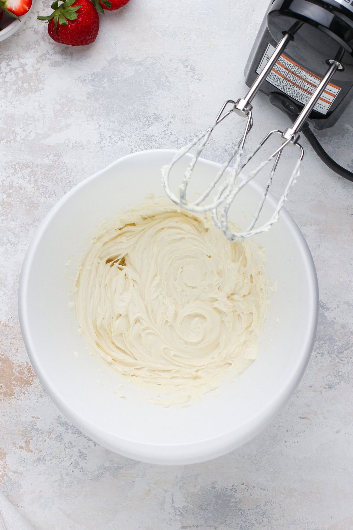 Beaten cream cheese in a white bowl.