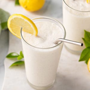 Glass of frosted lemonade garnished with a lemon slice.